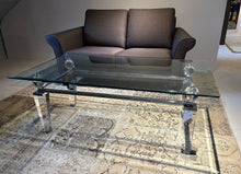 Laden Sie das Bild in den Galerie-Viewer, Eleganter Couchtisch aus Acryl und Glas von Kuatre, Ausstellungsstück auf Designteppich vor Frontansicht des Schröno Sofa Individual in braunviolettem JAB Anstoetz Stoff Vito 55 

