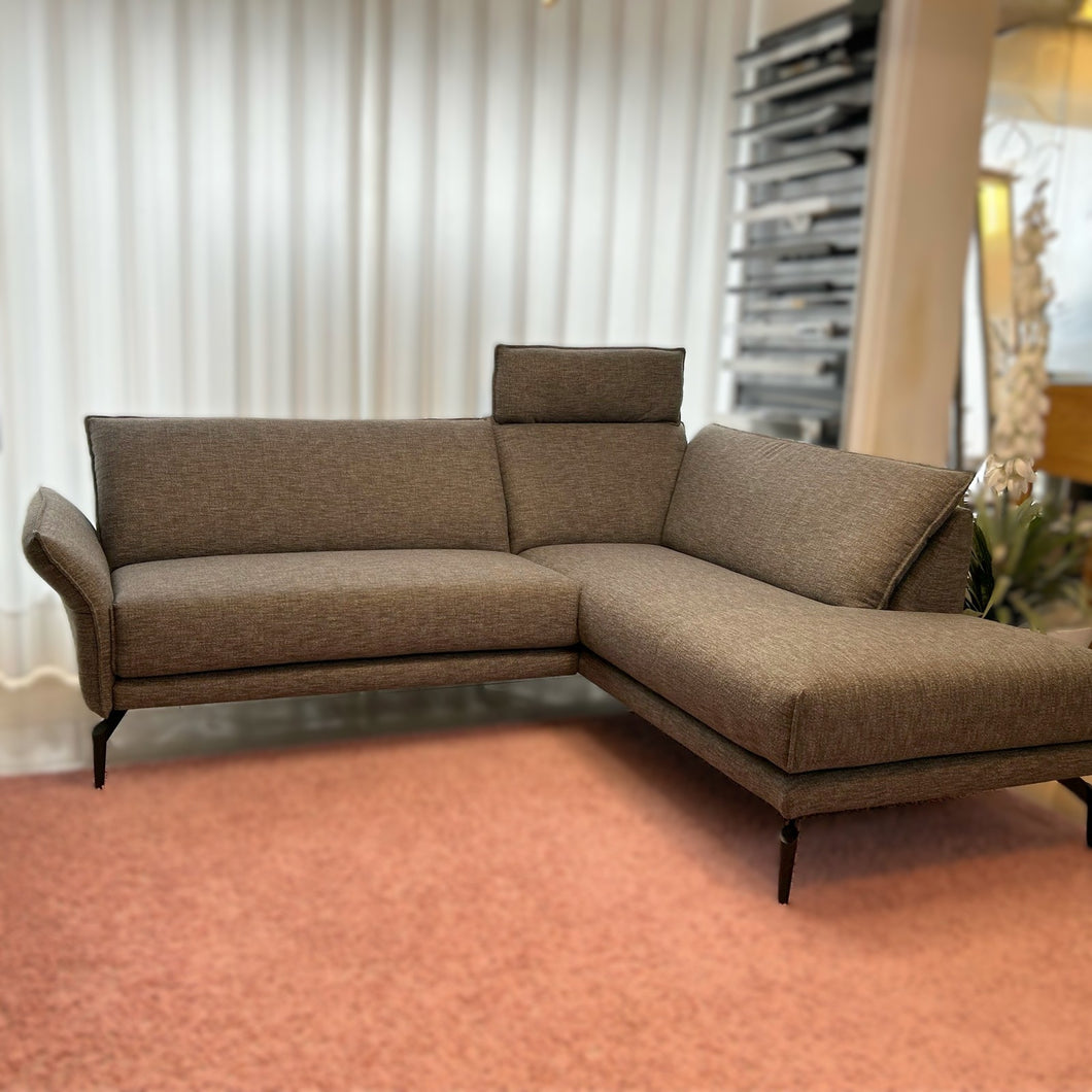 Modernes Ecksofa Violetta Modell Tilda in grauer Stoffausführung auf rosa Teppich – Ausstellungsstück im Möbelhaus Zeppenfeld in Olpe.