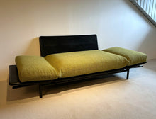 Laden Sie das Bild in den Galerie-Viewer, Dema Rataplan Sofa vollständig zur Liegefläche umgeklappt, beide Armlehnen flach gestellt, Funktion als Daybed demonstriert, schwarzes Untergestell und grüner Polsterstoff.
