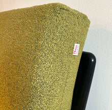 Laden Sie das Bild in den Galerie-Viewer, Detailaufnahme der grünen Rückenlehne des Rataplan Sofas mit sichtbarem Dema-Etikett, feiner Bouclé-Stoff in grün und schwarzer Metallrahmen im Hintergrund.
