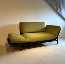 Laden Sie das Bild in den Galerie-Viewer, Funktionssofa Rataplan von Dema mit beiden Armlehnen teilweise abgeklappt, in Zwischenposition zum Daybed, grün bezogen mit schwarzem Gestell, moderne Loft-Atmosphäre.
