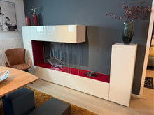 Laden Sie das Bild in den Galerie-Viewer, LAGO 36e8 Air Wohnwand mit geöffneter Klappe – hochwertige Innenverarbeitung und elegantes Glasdesign in Lack Weiß mit Akzent Rosso
