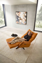 Laden Sie das Bild in den Galerie-Viewer, Nolte Lounger Miami in vollständiger Herz-Waage-Position, orangefarbenes Nappaleder, Frau entspannt liegend – ergonomischer Komfort in modernem Interieur.
