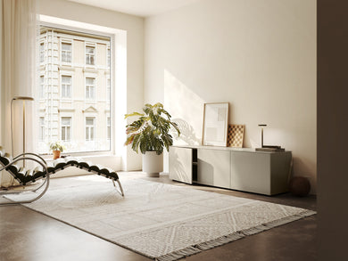Piure Nex Pur Box 2020600 in Silk in heller Wohnumgebung – 3-türiges Sideboard unter Fenster, dekorativ inszeniert mit Kunst, Lampe und Pflanzen.