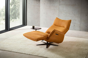 Der Nolte Lounger Miami in relaxter Sitzposition mit ausgestelltem Fußteil – moderner Designstuhl in stilvollem Ambiente mit großem Fenster.