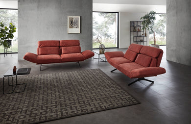Seitenansicht des Relaxsofas Meda mit verstellbarer Rückenlehne in tiefrotem Leder – stilvolle Kombination aus Gemütlichkeit und geometrischer Eleganz.