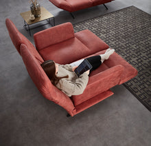 Laden Sie das Bild in den Galerie-Viewer, Frau liegt bequem in Relaxposition auf dem Meda Sofa von Nolte – alle Elemente individuell angepasst, von Rücken bis Beinauflage, für höchsten Komfort im Alltag.
