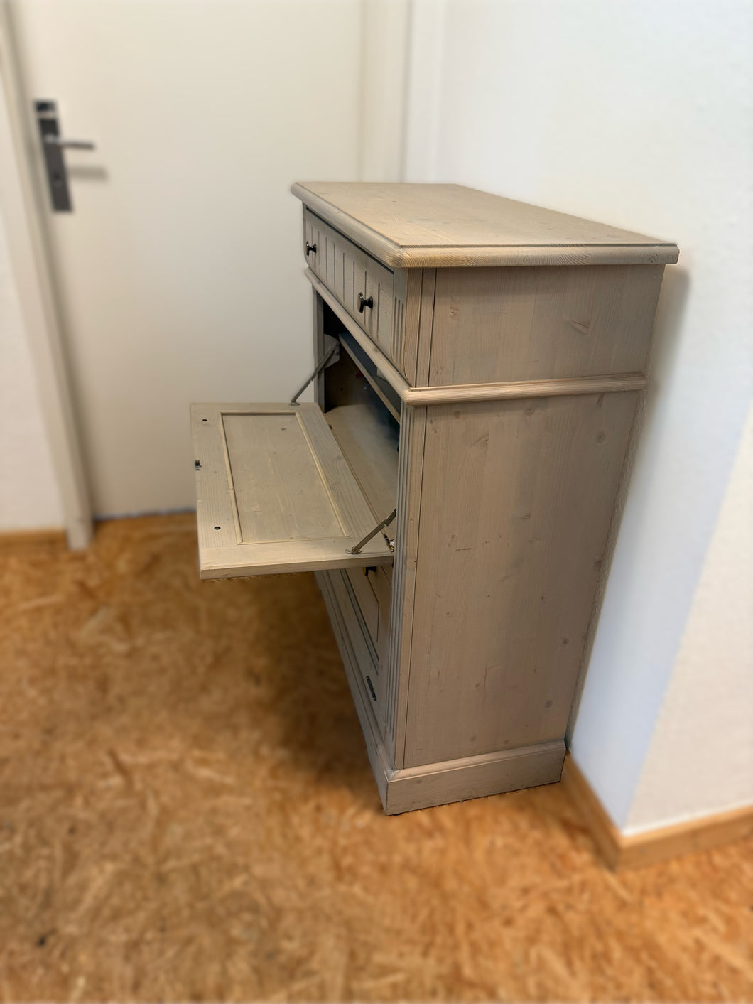 Detailansicht der Klappenmechanik der Gradel Schuhkommode 2283, sichtbar geöffnete Klappe mit Innenraum zur Schuhaufbewahrung, leichte Lagerspuren erkennbar