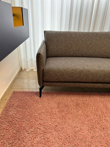 Modernes Design-Ecksofa Violetta Tilda im Möbelhaus Zeppenfeld, umgeben von Stoffmustern und stilvoller Dekoration.