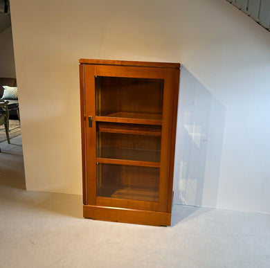 Form Exclusiv Vitrine „Premium“ 1-türig in Kirschbaum, Frontansicht im Raum, Ausstellungsstück mit Original-Transportleisten, feine Messingbeschläge, sofort verfügbar.